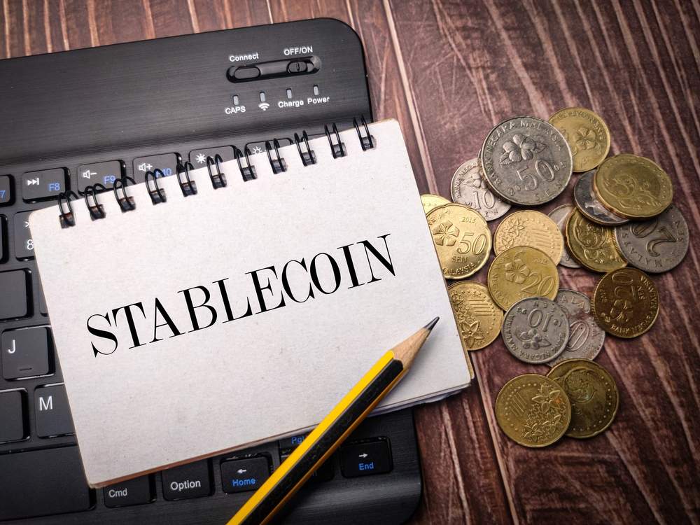 Notebook with Stablecoin written and various coins on desk